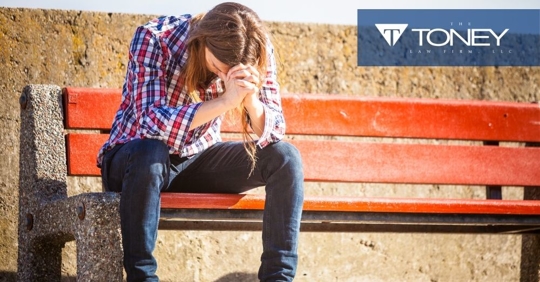 man sitting on bench with head resting on hands